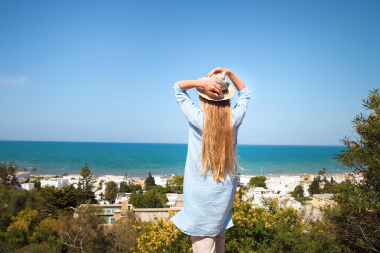 Vue d’une femme face à la mer sur la côte tunisienne, illustrant des activités et visites réalistes pendant un séjour médical en Tunisie.